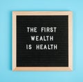 The first wealth is health. Motivational quote on black letter board on blue background. Concept Health Care and Medicine,