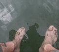 Firts person view of a male feets into lake water with small fish