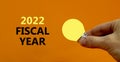 2022 fiscal new year symbol. Businessman holds yellow shining light bulb. Words `2022 fiscal year`, isolated on beautiful orange