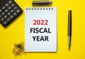 2022 fiscal new year symbol. White note, words 2022 fiscal year on beautiful yellow table, paper clips, metallic pen and