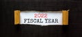 2022 fiscal new year symbol. Words `2022 fiscal year` appearing behind torn black paper. Beautiful black background. Business,