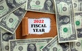 2022 fiscal new year symbol. Words `2022 fiscal year` appearing behind torn brown paper. Beautiful background from dollar bills.