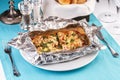 Fish baked in a foil with tomatoes, entirely with onion rings, red and green peppers, chili peppers, greens, cheese, mushrooms Royalty Free Stock Photo