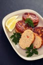 Fish balls with lemon on dish on black ceramic background