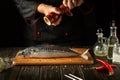 Fish chef prepares fresh mackerel in the kitchen. Scomber must be added with aromatic pepper before baking. European cuisine Royalty Free Stock Photo