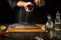 Fish chef prepares fresh mackerel in the kitchen. Scomber must be added with aromatic pepper before baking. European cuisine Royalty Free Stock Photo