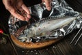 The fish chef prepares Scomber in the hotel kitchen. Before baking, mackerel must be wrapped in foil and spices added Royalty Free Stock Photo