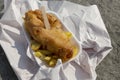 Fish and chips, battered cod, in a tray wrapped in paper on a beach. Traditional British food concept Royalty Free Stock Photo