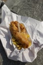 Fish and chips, battered cod, in a tray wrapped in paper on a beach. Traditional British food concept Royalty Free Stock Photo