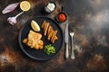 fish and chips with beer-battered cod and fries and a side of tartar sauce and mushy peas on black plate over old rustic metal Royalty Free Stock Photo