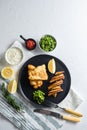 fish chips with beer-battered cod and fries and a side of tartar sauce and mushy peas on rustic white stone table top view space Royalty Free Stock Photo