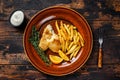 Fish and Chips british fast food with french fries and tartar sauce on a rustic plate. Dark wooden background. Top view Royalty Free Stock Photo