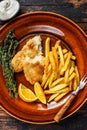 Fish and Chips british fast food with french fries and tartar sauce on a rustic plate. Dark wooden background. Top view Royalty Free Stock Photo