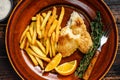 Fish and Chips british fast food with french fries and tartar sauce on a rustic plate. Dark wooden background. Top view Royalty Free Stock Photo