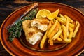 Fish and Chips british fast food with french fries and tartar sauce on a rustic plate. Dark wooden background. Top view Royalty Free Stock Photo