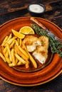 Fish and Chips british fast food with french fries and tartar sauce on a rustic plate. Dark wooden background. Top view Royalty Free Stock Photo