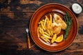 Fish and Chips british fast food with french fries and tartar sauce on a rustic plate. Dark wooden background. Top view Royalty Free Stock Photo