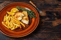 Fish and Chips british fast food with french fries and tartar sauce on a rustic plate. Dark wooden background. Top view Royalty Free Stock Photo