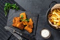 Fish and chips, French fries and cod fillet fried in breadcrumbs. Black background. Top view