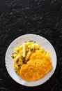 Fried fish fillet in cheese and potatoes in a white plate on black background. with copy space. top view Royalty Free Stock Photo