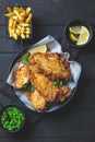 Fish and chips with green peas on dark background. British cuisine concept Royalty Free Stock Photo