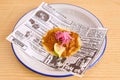 Fish and chips on a plate with newspaper on a wooden table