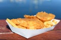 Fish and Chips served in a tray on a waterfront restaurant table