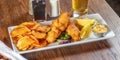 Fish and chips are served on a white plate, accompanied by lime wedges Royalty Free Stock Photo