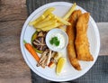 fish and chips serving with french fries and salad white sauce. hot salmon and cod seafood in white circle plate Royalty Free Stock Photo