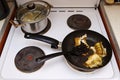 Fish cooked in a frying pan on an electric stove. The lid is open. Unhealthy fatty foods.