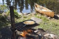 Fish cooking outdoors in a frying pan with a canoe in the backgr Royalty Free Stock Photo