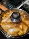 Fish curry stew simmering in pan with glass lid.