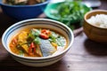 fish curry with tomatoes and cilantro in a ceramic bowl