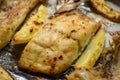 Fish dish cooked on oiled paper in the oven and potatoes on the side