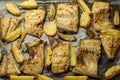 Fish dish cooked on oiled paper in the oven and potatoes on the side