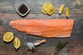 Fish fillet with culinary ingredients, salt, herbs, pepper, and lemon. raw Atlantic salmon fillet on skin on dark wooden board Royalty Free Stock Photo