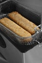 Fish fingers in a mesh basket, cooked in an electric deep fat fryer appliance.