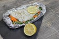 Fish in foil on a stone baked with lemon and vegetables Royalty Free Stock Photo