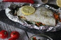 Fish in foil on a stone baked with lemon and vegetables Royalty Free Stock Photo