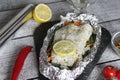 Fish in foil on a stone baked with lemon and vegetables Royalty Free Stock Photo