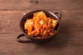 Fish marinated with carrots in a brown ceramic bowl on old wooden table