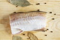 Fish meat with spice closeup. Pepper peas and bay leaf for seasoning. Top view on wooden background