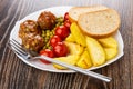 Fish meatballs with potato, tomatoes and green peas, fork pieces