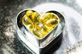 Fish oil capsule on double heart shape box in smaller one on bl Royalty Free Stock Photo