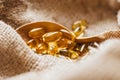 Fish oil capsules on a wooden spoon. Fish oil pills, tablets on the burlap Royalty Free Stock Photo