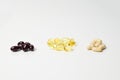 Fish oil, multivitamins and astaxanthin capsules in three bunches. Omega-3 in the middle. White background. Close-up