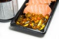 Fish oil pills served with salmon sushi on black pack with brown Royalty Free Stock Photo