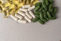 fish oil pills and white capsules, green pills on a light gray background. translucent gelatin capsules, white non-transparent cap