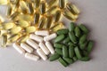 fish oil pills and white capsules, green pills on a light gray background. translucent gelatin capsules, white non-transparent cap