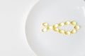 Fish oil softgels on a white plate in a shape of a fish. Meal replacement. Nutrition prescription. Omega-3 polyunsaturated fatty